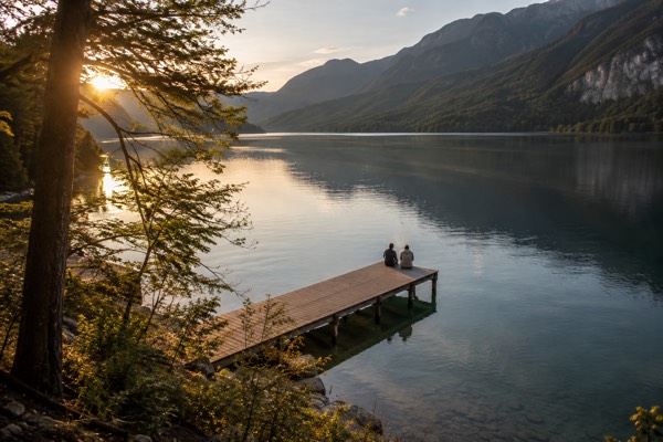 A long quiet alpine lake ringed by forest, a wooden jetty running out into the still water, Lake Bohinj, Bohinj