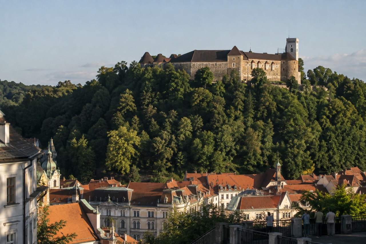 Ljubljana old town rooftops under a clear summer sky with the castle hill rising behind