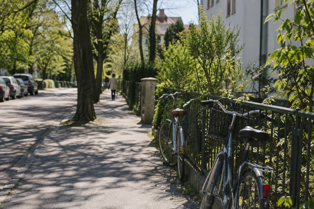 Quiet tree-lined residential street in Trnovo with bicycles leaning against a railing
