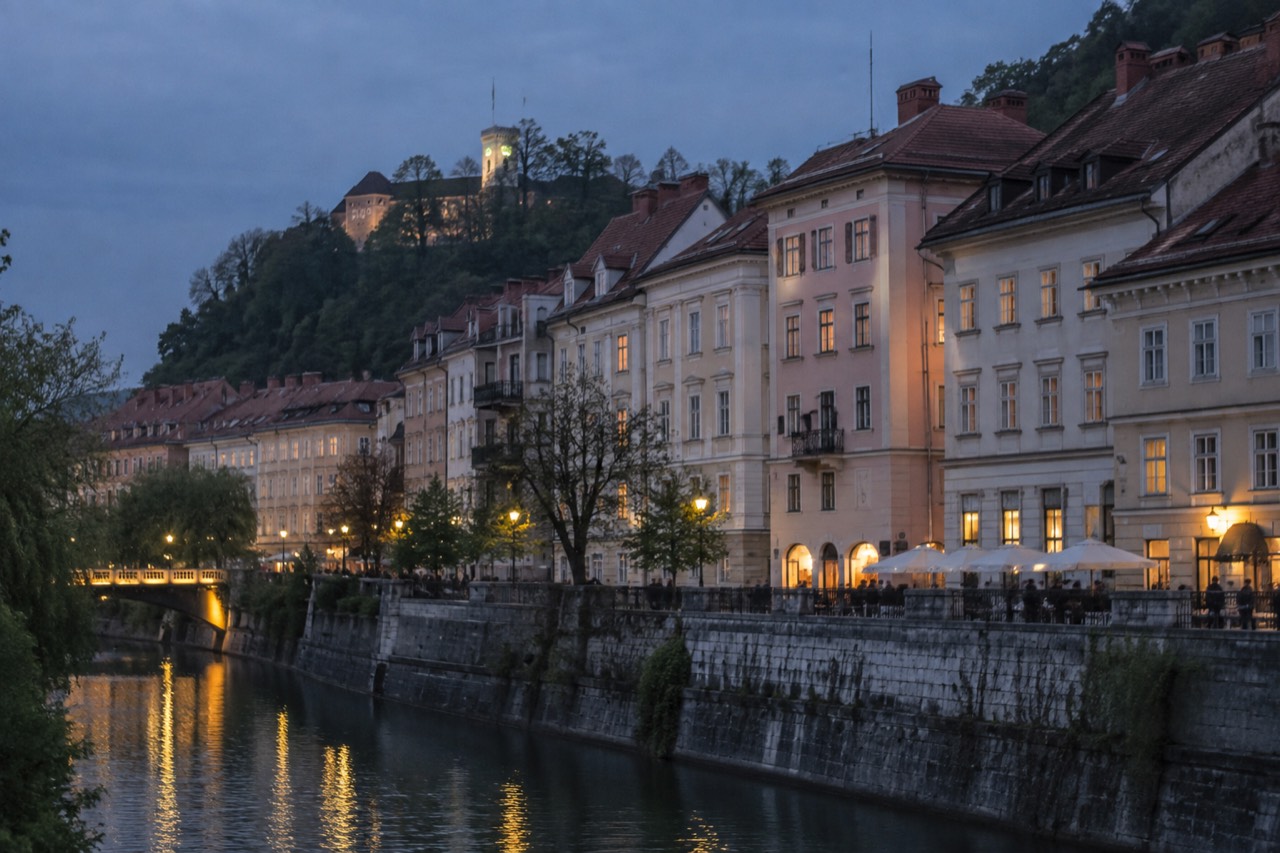 Pastel facades and rooftops of Ljubljana old town seen across the Ljubljanica river at dusk