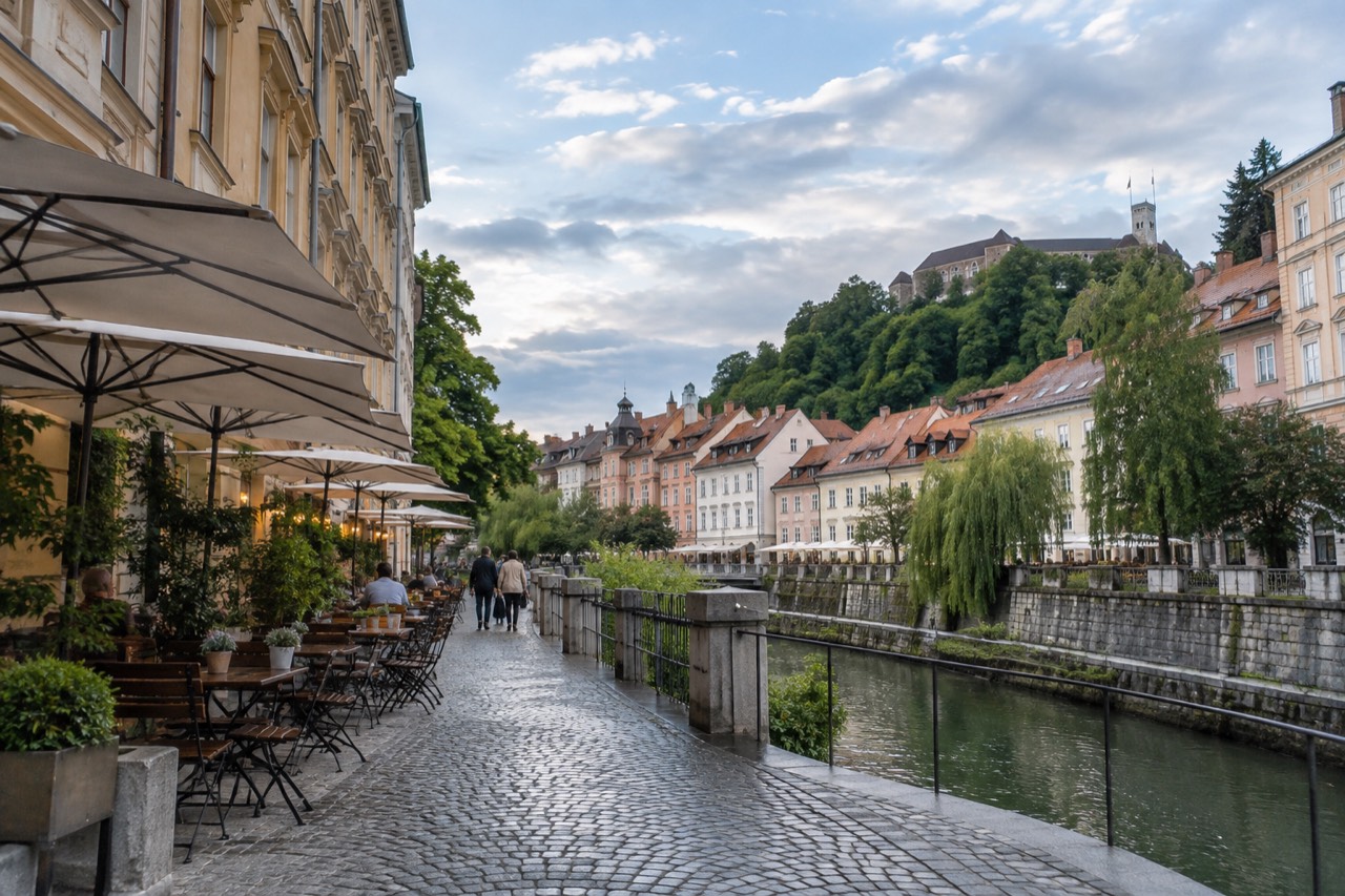 Outdoor restaurant tables beside a riverside street in central Ljubljana