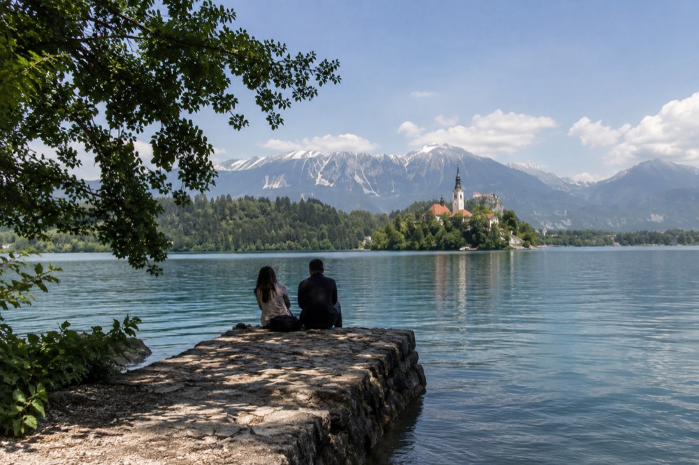 Small stone jetty extending into Lake Bled with the island church in the distance