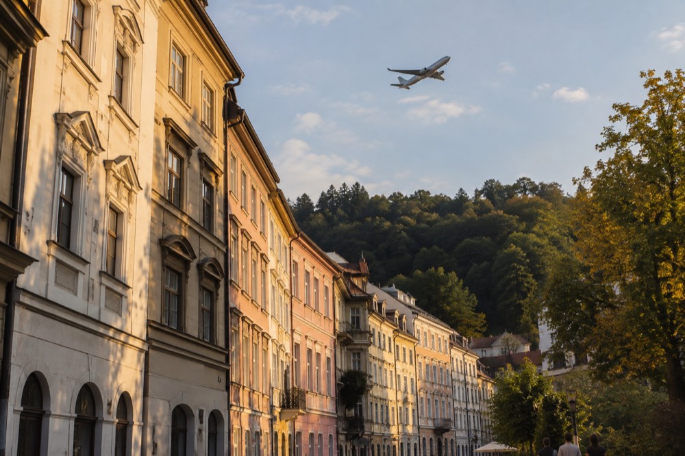 A passenger aircraft banking over green hills on approach to a small airport