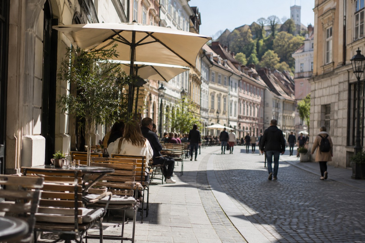 Café tables along a pedestrian street in central Ljubljana on a bright morning