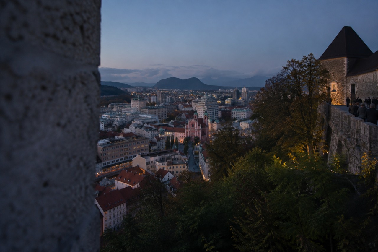 A view over the tiled roofs and church towers of central Ljubljana with the Ljubljanica river winding below the castle hill