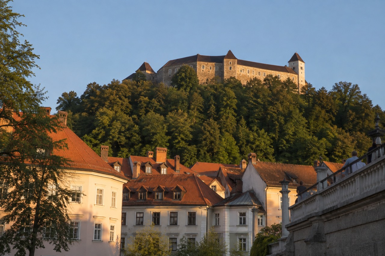 Ljubljana Castle towers above the red rooftops of the old city centre under a clear sky