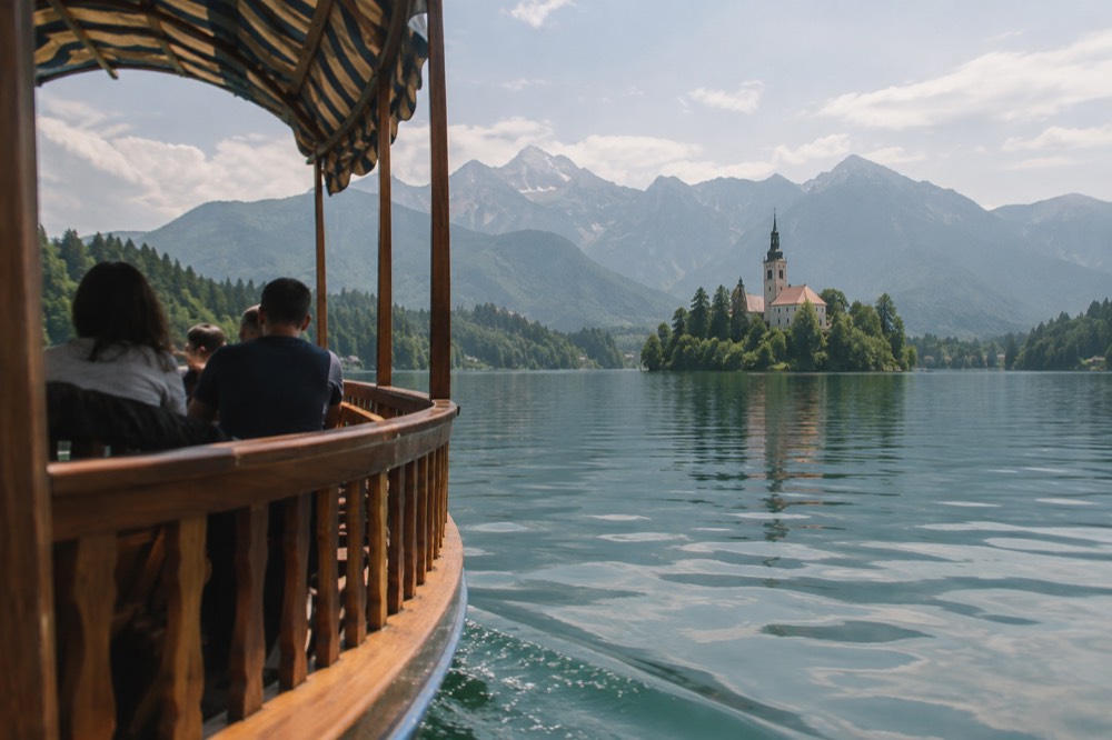 Bled Island church seen across the lake with a wooden pletna boat in the foreground