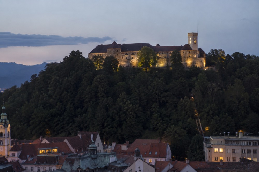 The viewing tower on Ljubljana Castle hill above the rooftops of the old centre at dusk