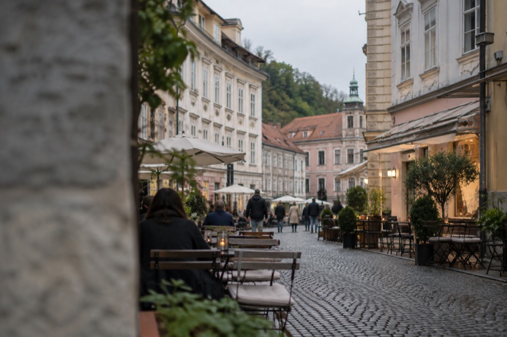 A car-free cobbled street in Ljubljana Old Town lined with outdoor cafe tables