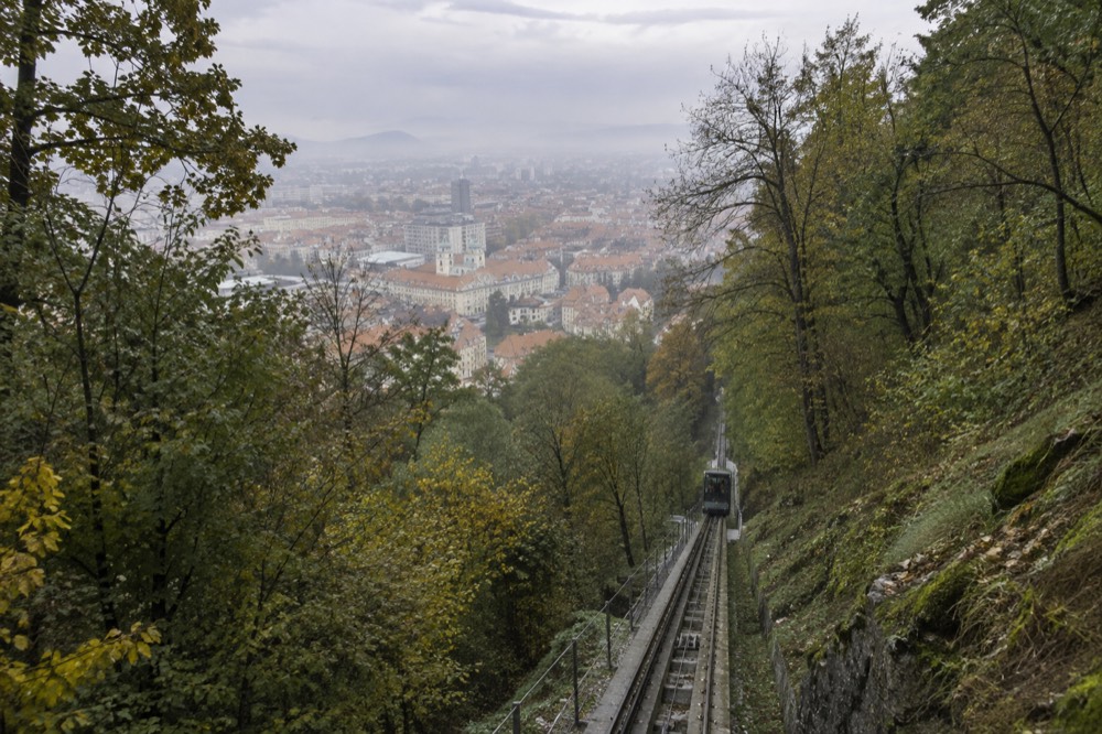 The funicular railway climbing the wooded hillside toward Ljubljana Castle above the city rooftops
