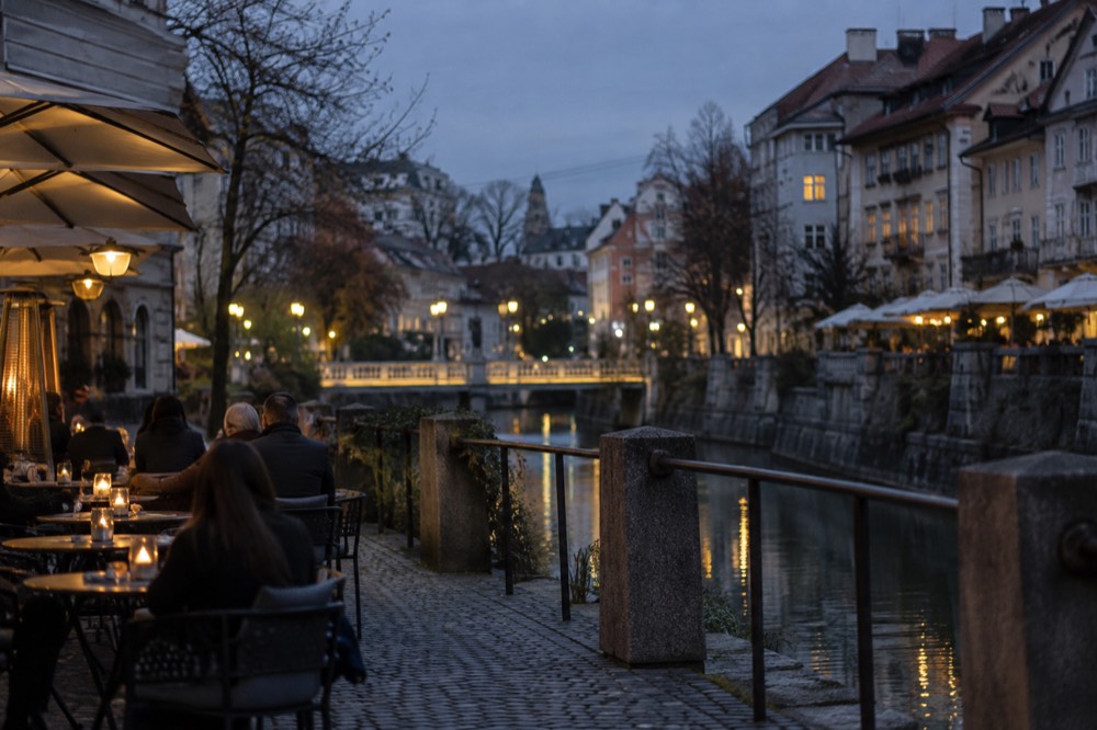 Café tables on a cobbled street beside the Ljubljanica river in Ljubljana