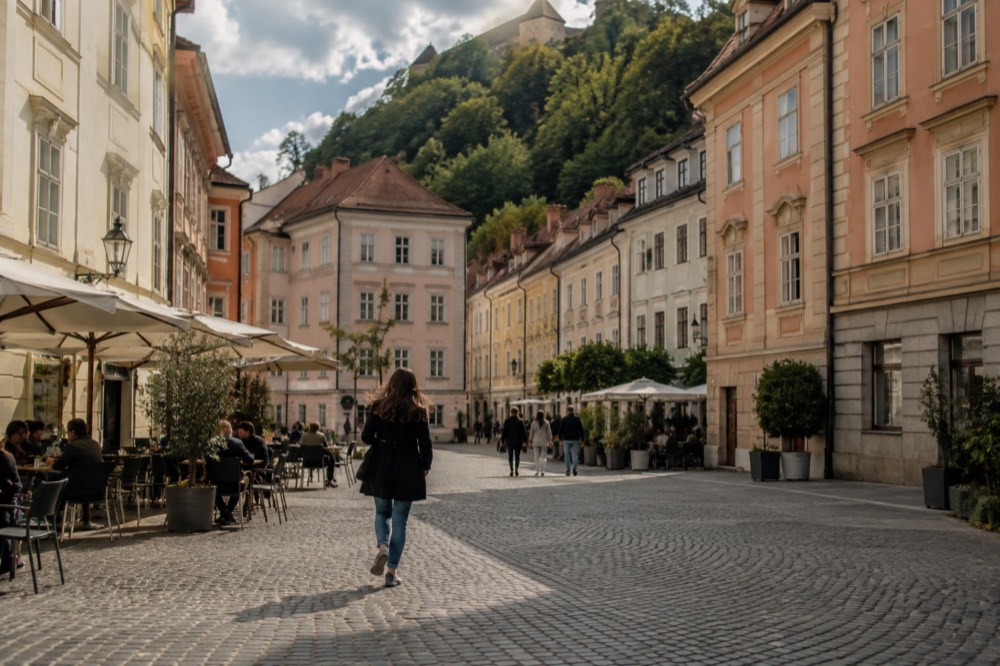 Cobblestone square in Ljubljana's old town with cafe tables and pastel facades