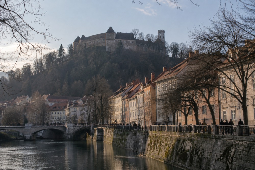 Ljubljana Castle on its hill above the city rooftops seen from the river