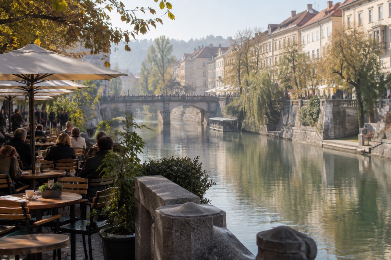 Outdoor cafe tables beside the Ljubljanica river in central Ljubljana on a bright afternoon