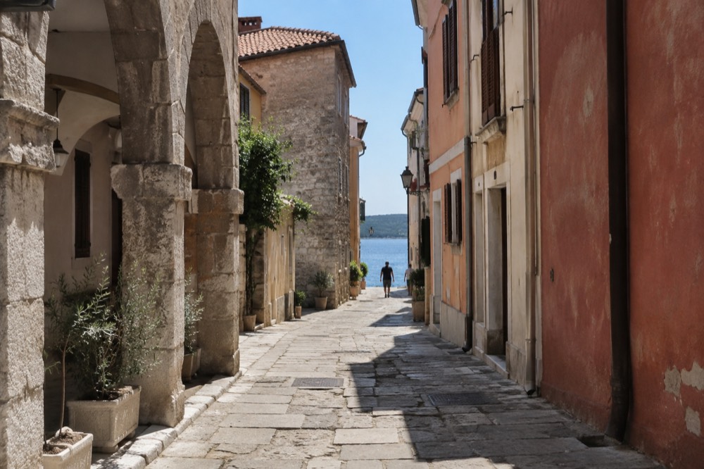 Narrow lane with pastel houses and stone arches in Koper