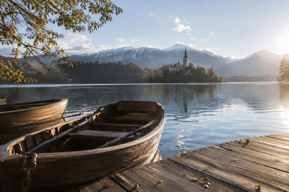 The island church on Lake Bled seen from the shore path with rowing boats moored nearby