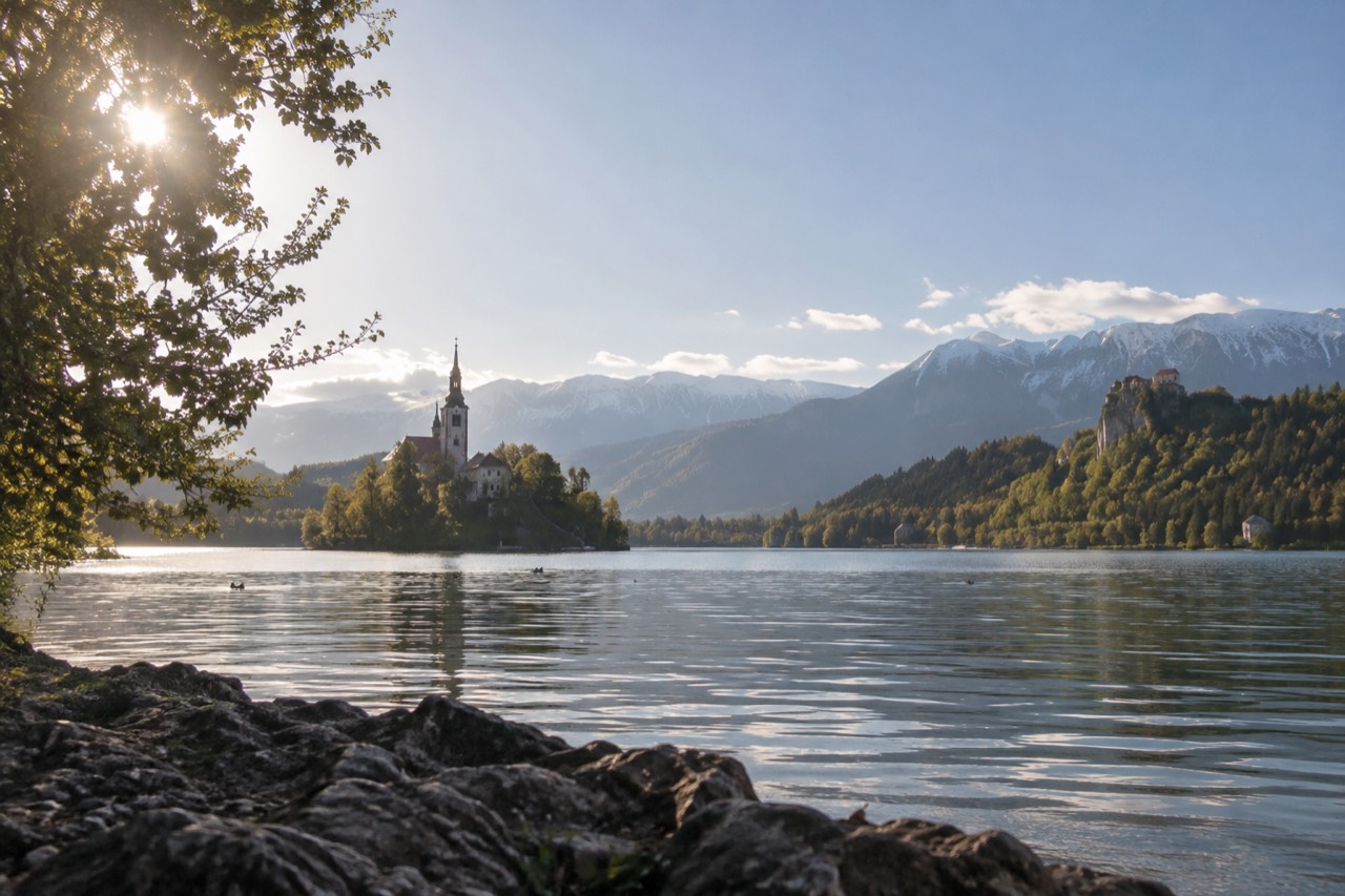 Lake Bled with the island church and castle walls above the shore on a clear morning