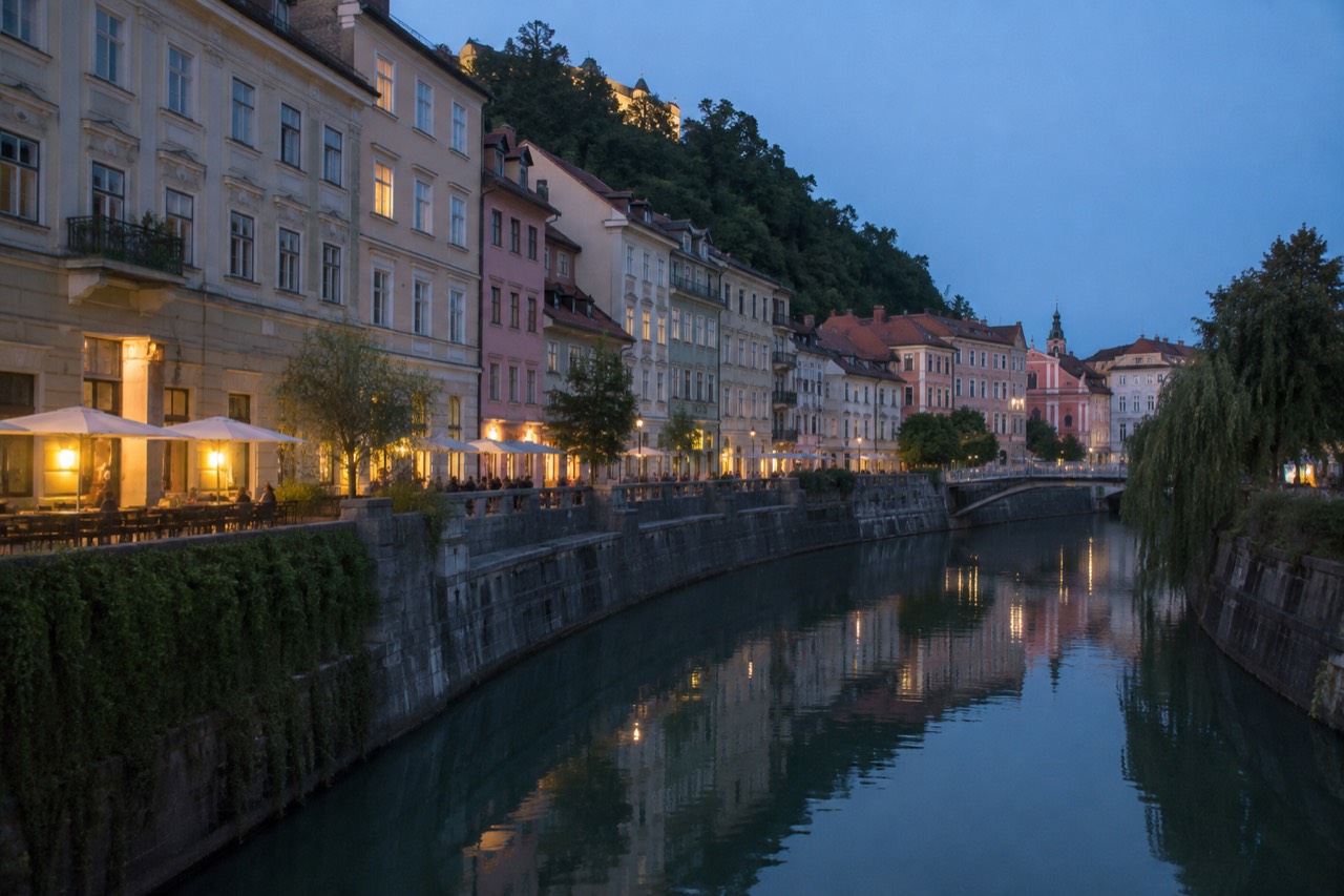 Pastel buildings reflected in a calm river through a Slovenian old town