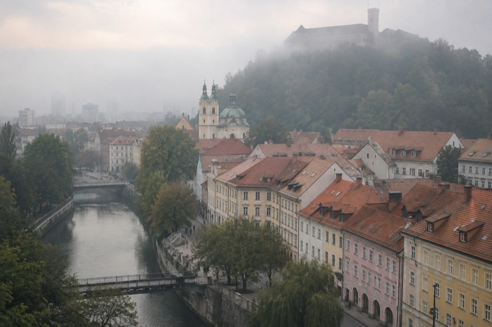 Fog lying over a river town with a hilltop castle rising above it
