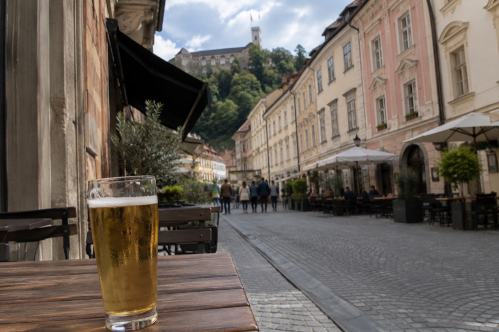 A half-litre glass of pale lager on a pub table in a narrow old town street