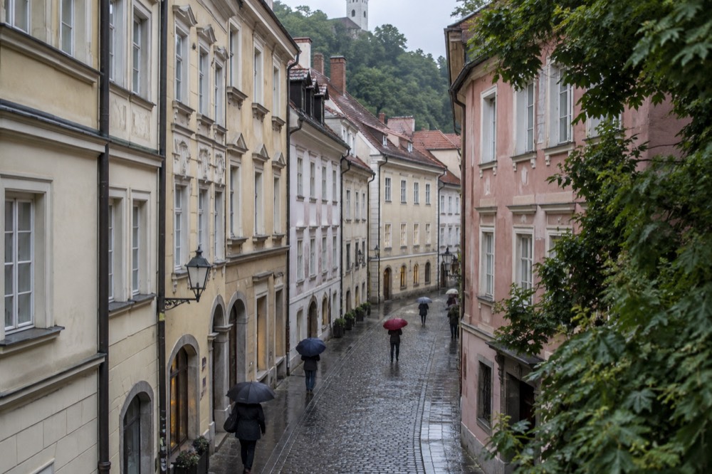 Wet cobblestone street in the Ljubljana old town with umbrellas