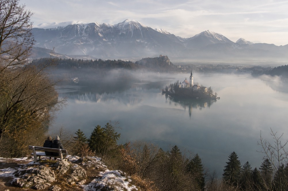 Morning mist over Lake Bled with the island and distant Julian Alps