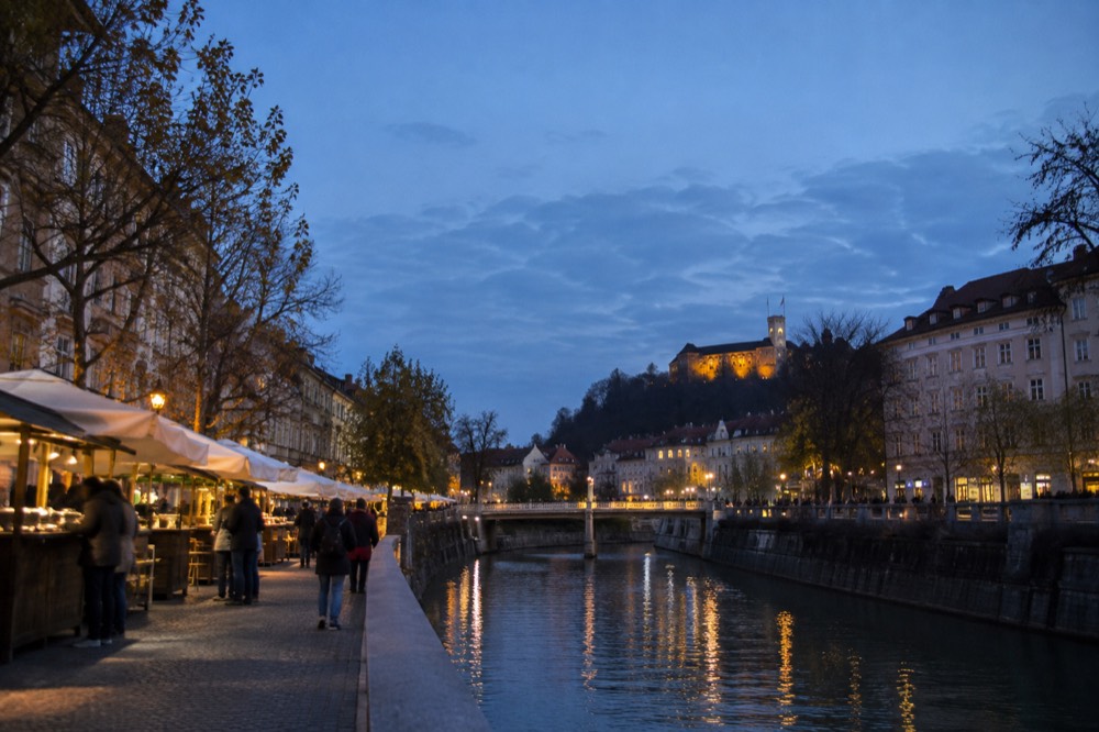 Outdoor food stalls beside the Ljubljanica river in central Ljubljana at dusk