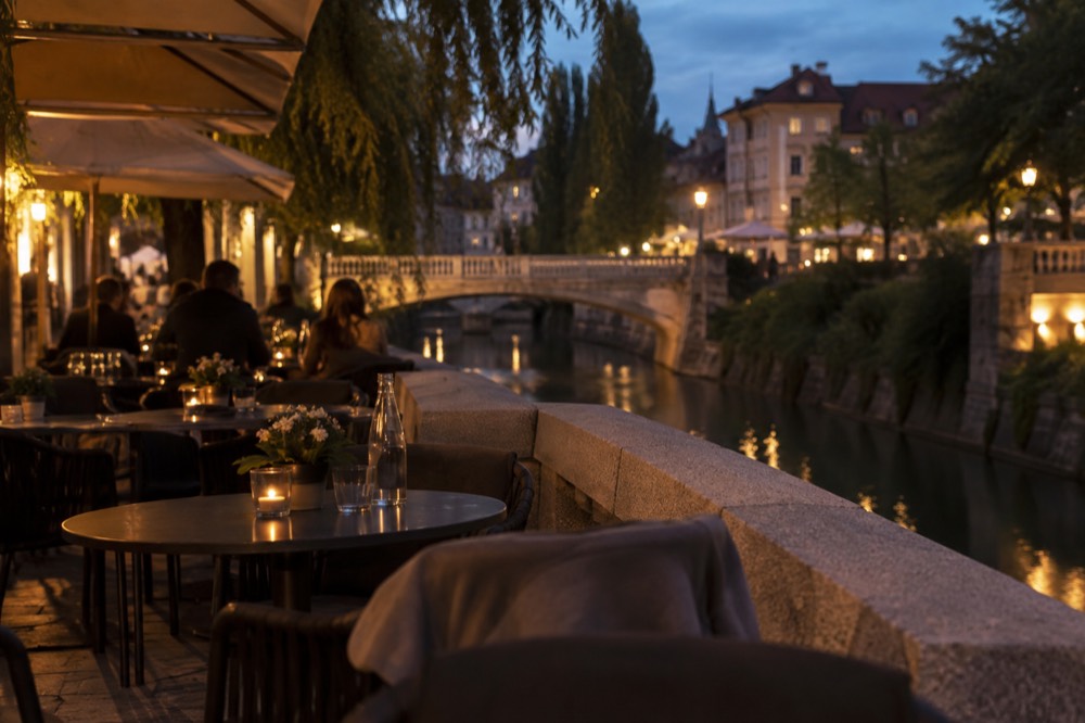 Café tables along the Ljubljanica riverbank in the evening