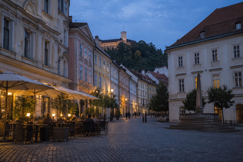 A quiet cobbled square in Ljubljana with café tables and baroque facades