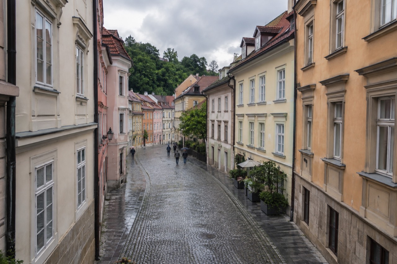 Cobblestone street in Ljubljana old town with pastel coloured buildings under a cloudy sky