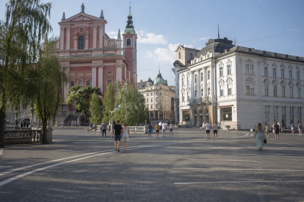 Prešeren Square with the pink Franciscan church facade and arcade buildings under a clear sky