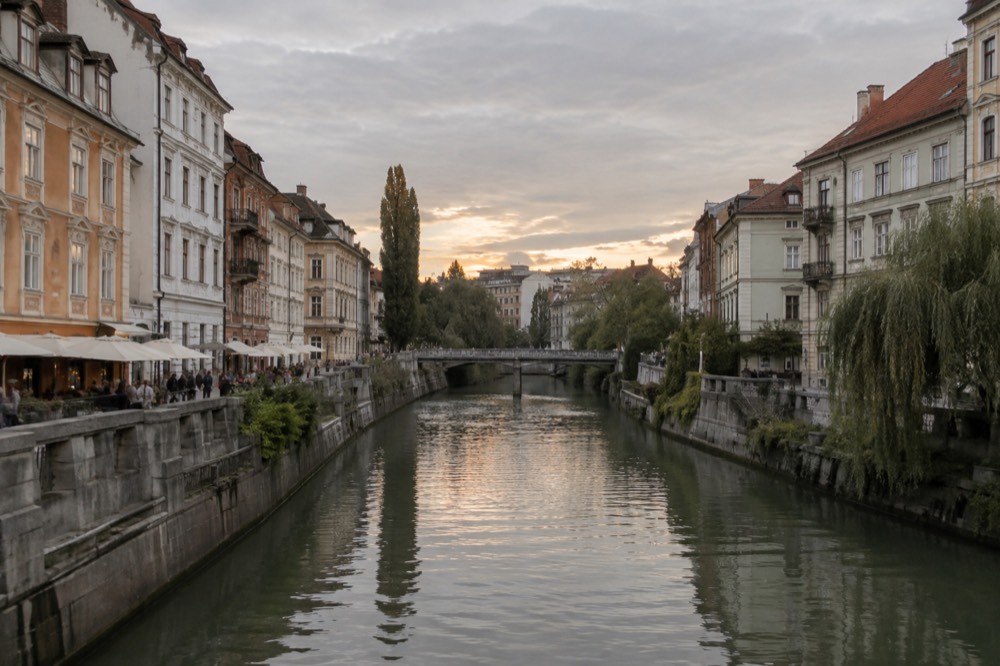 Pastel coloured baroque buildings along the Ljubljanica river in Ljubljana at golden hour
