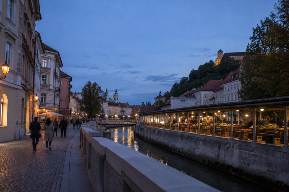 Open-air market stalls under a colonnade beside the river