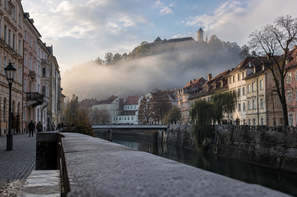 Fog partially filling a river valley with a hilltop castle in clearer light above