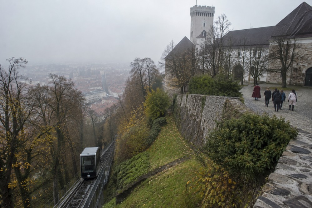 A guide in historical costume leading a small group across the castle courtyard toward the Viewing Tower