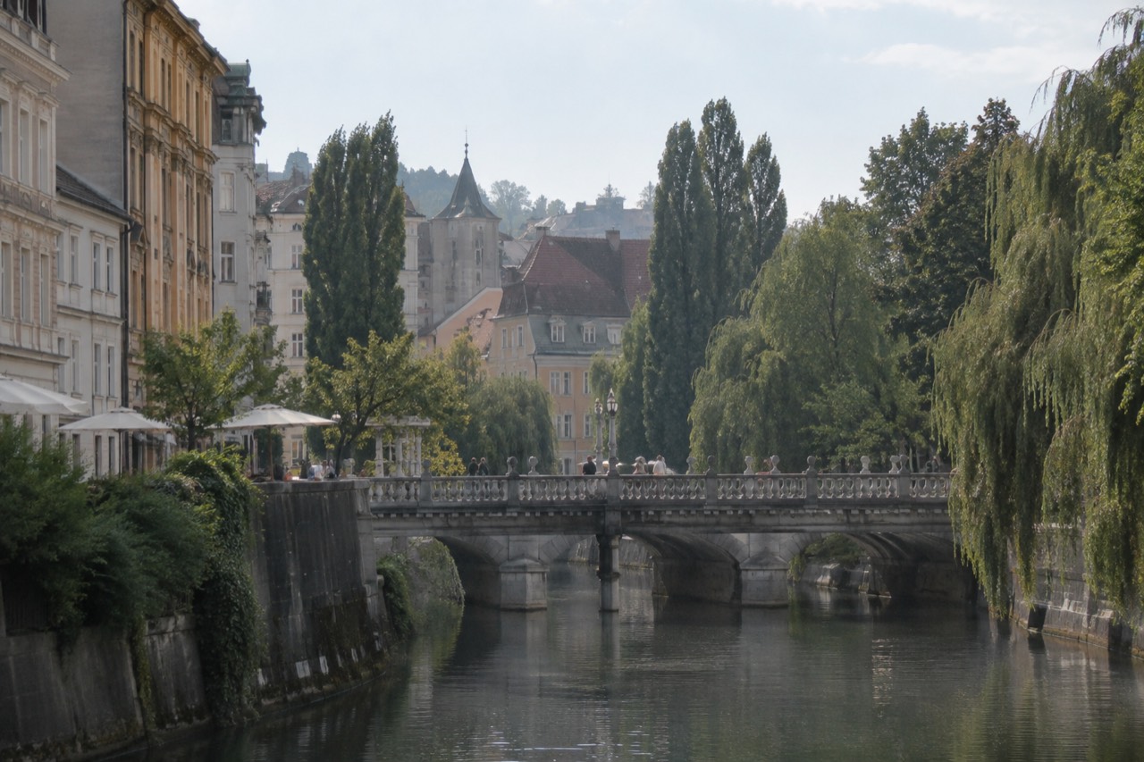 Stone bridge with four dragon statues at its corners crossing a river through a city centre