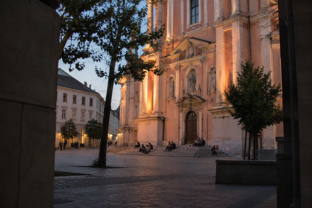 The church facade in golden evening light with people seated on the steps