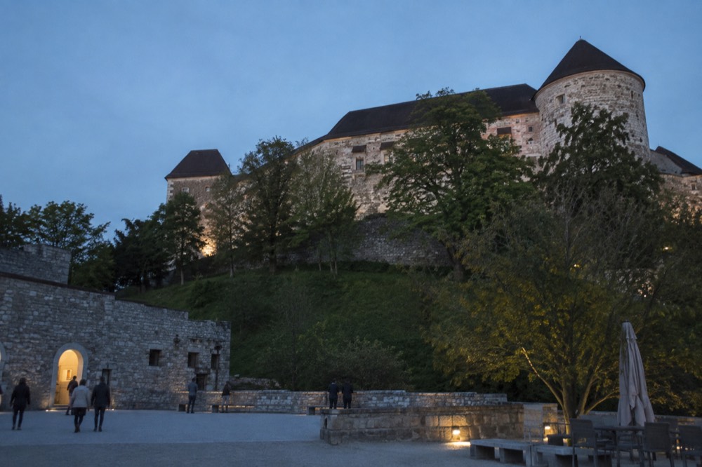 Stone castle walls and a round tower above a green hillside