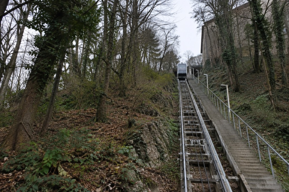 A funicular carriage climbing a steep rail track beside stone steps