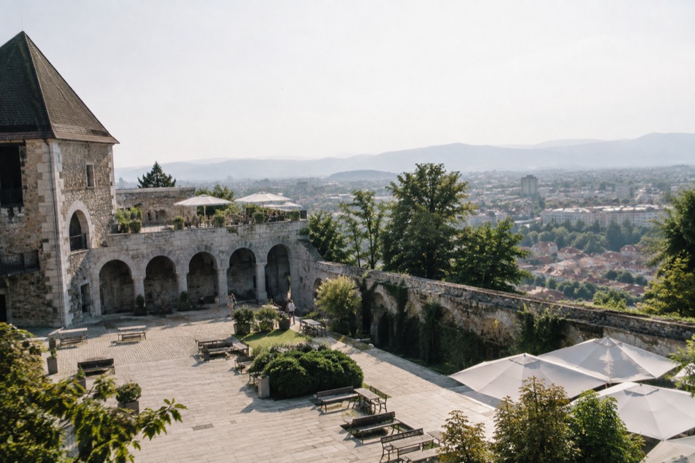 A castle courtyard with stone arcades and open wooden benches