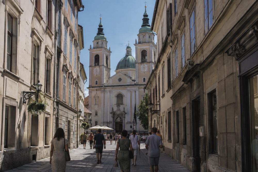 The twin bell towers and green dome of the cathedral seen from a narrow old street