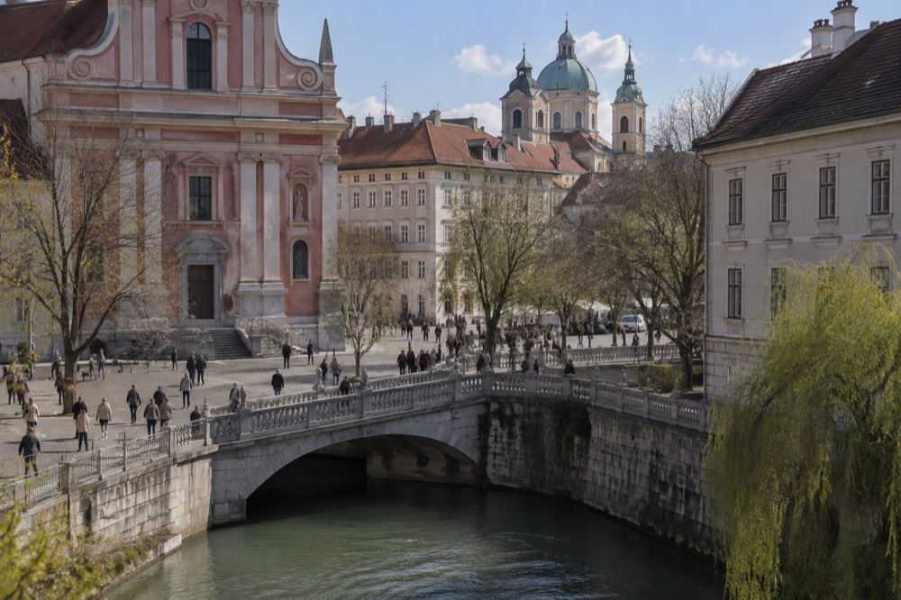 A riverside embankment with a stone bridge and church domes above the rooftops