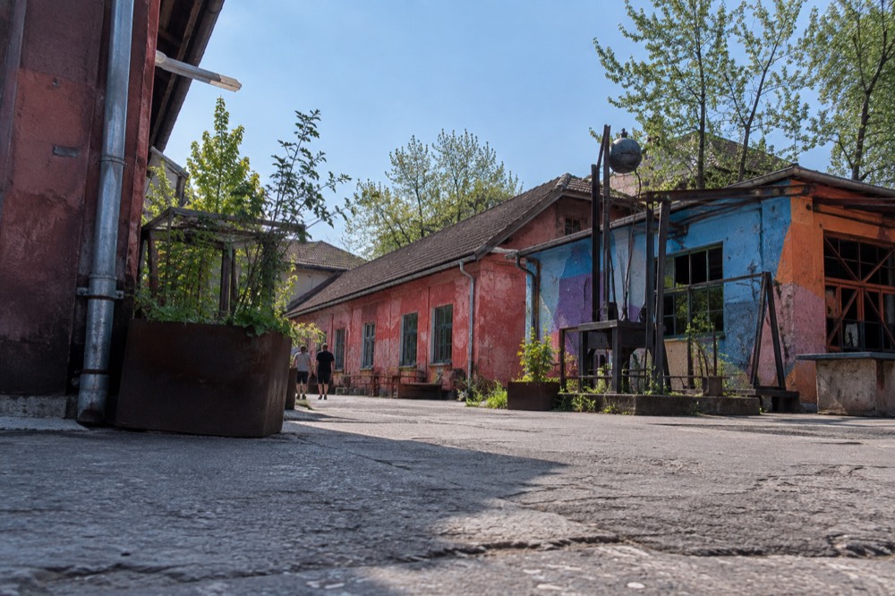 paint-covered walls and welded metal sculptures along a barracks wall