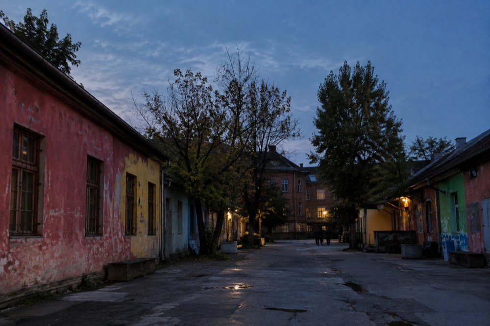 A tree-lined street leading toward brick barracks buildings
