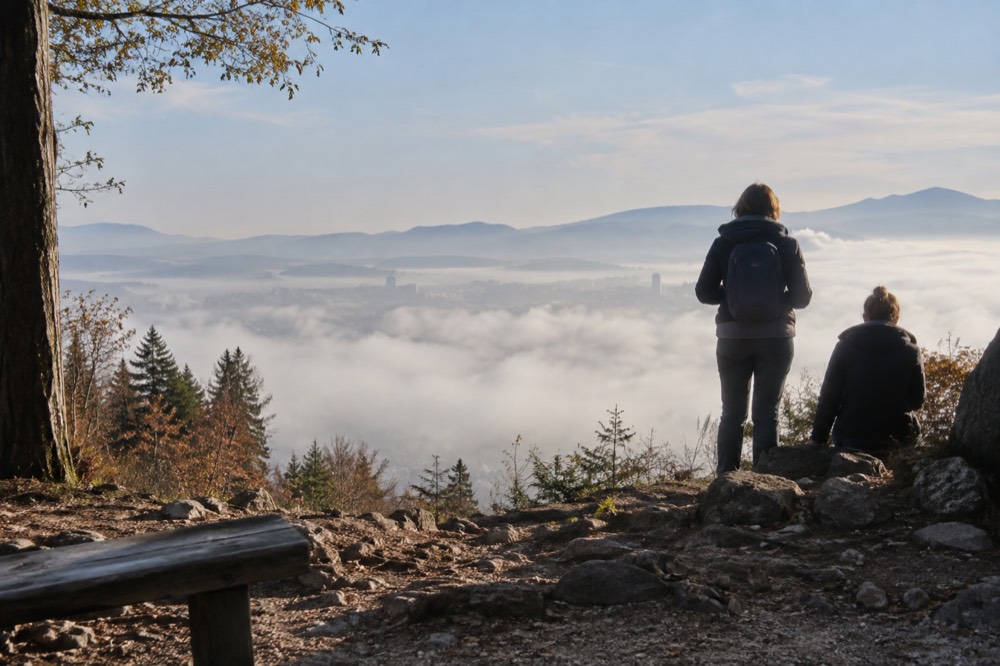 Hikers on a hilltop terrace above a layer of fog covering a city below