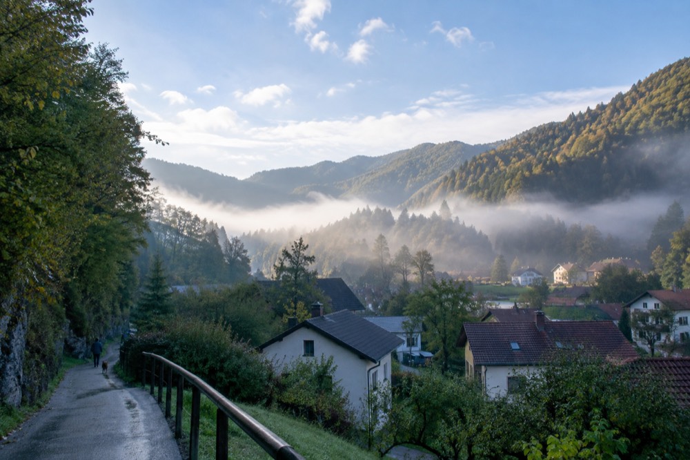 morning mist filling a valley below sunlit forested ridges