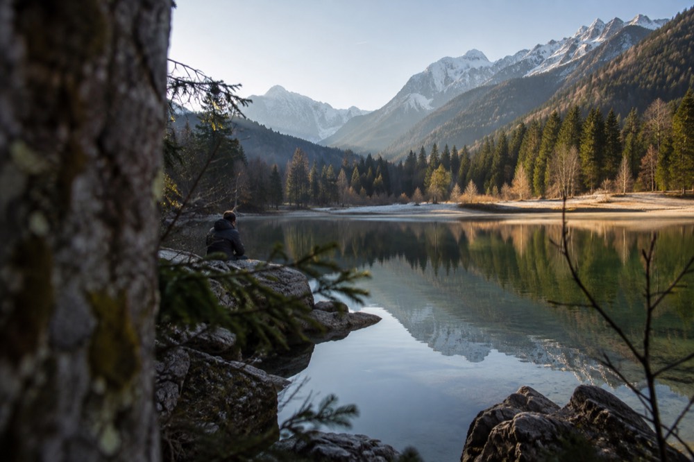 A small alpine lake with clear water and mountains reflected on the surface