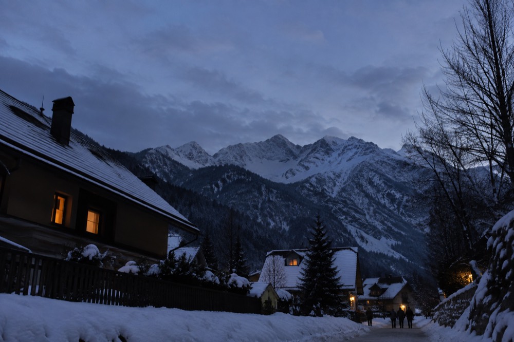 Village rooftops dusted with snow beneath a white mountain range