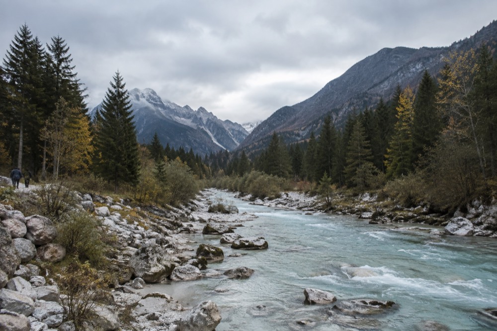 A turquoise alpine river flowing between forested valley slopes