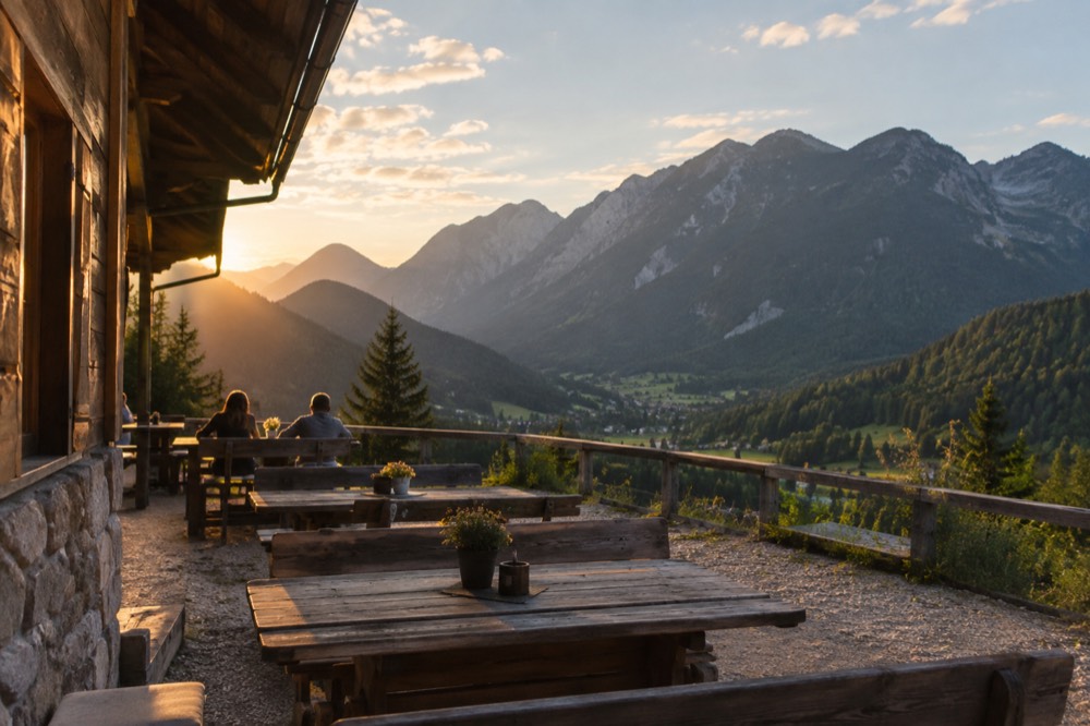 A mountain hut terrace with wooden benches overlooking a green valley